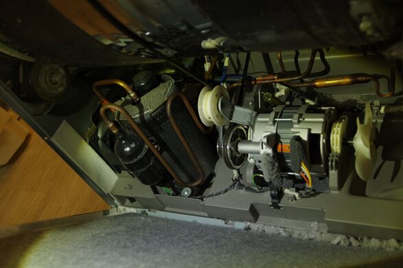Drive motor, idler pulley, fan and compressor, seen from under the drum. Some lint on the floor of the base, but nothing like the evaporator coil